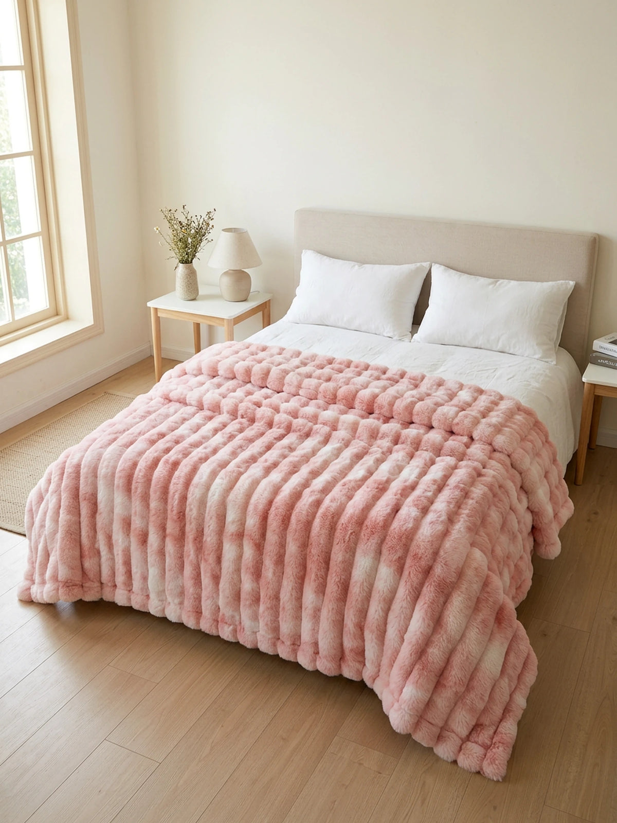 Kunstfelldecke in Pink auf einem Doppelbett im hellen Schlafzimmer